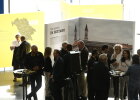 Gäste bei der Ausstellungseröffnung mit Ausstellung im Hintergrund