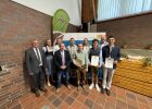 Gruppenfoto mit fünf jungen Absolventinnen und Absolventen mit Urkunden sowie mehreren Ehrengästen und Offiziellen vor einem Roll-Up der Regierung der Oberpfalz. Aufnahme bei der Freisprechungsfeier in Weiden/Almesbach.