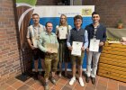 Fünf junge Erwachsene stehen mit Urkunden vor einem Roll-Up der Regierung der Oberpfalz. Sie stammen aus den Landkreisen Amberg-Sulzbach und Schwandorf und nahmen an der Freisprechungsfeier in Weiden/Almesbach teil. Mehrere Personen tragen Tracht.