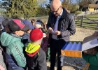Regierungspräsident Walter Jonas steht mit einer Gruppe von Schulkindern zusammen und zeigt ihnen Eier auf dem Bauernhof.