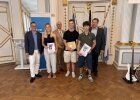 Zwei Schüler des Gymnasiums Eschenbach präsentieren ihre Urkunde und einen Preisumschlag gemeinsam mit Vertretern der Schule und der Regierung.