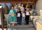Absolventinnen der Berufsfachschule Sulzbach-Rosenberg präsentieren auf einer Treppe ihre Urkunden.